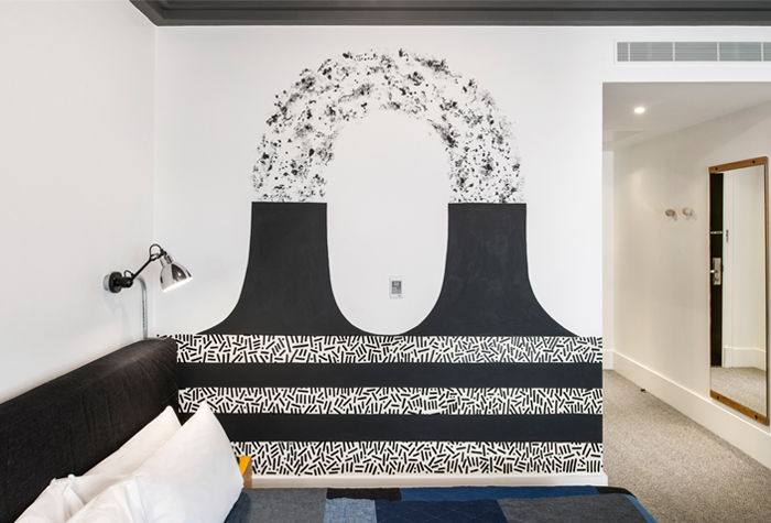 Black and white wall painting behind a hotel bed