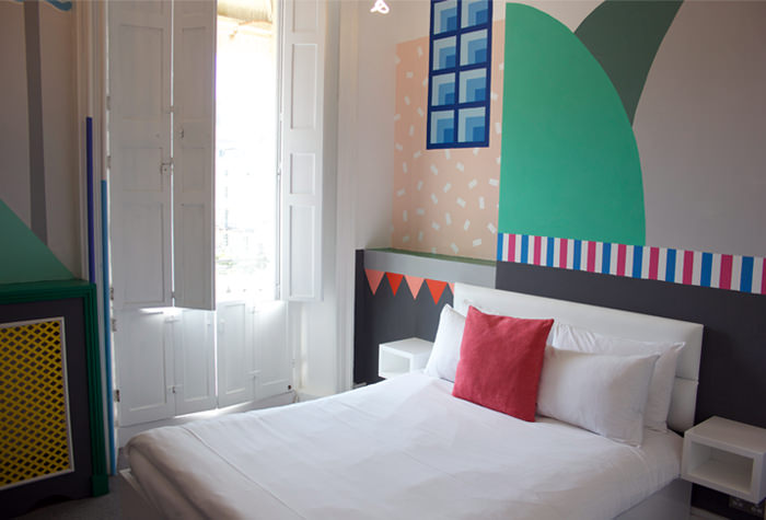 Bedroom with a green and pink geometric wall painting