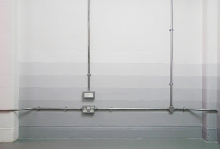 Office wall with exposed pipes above a pale grey gradient