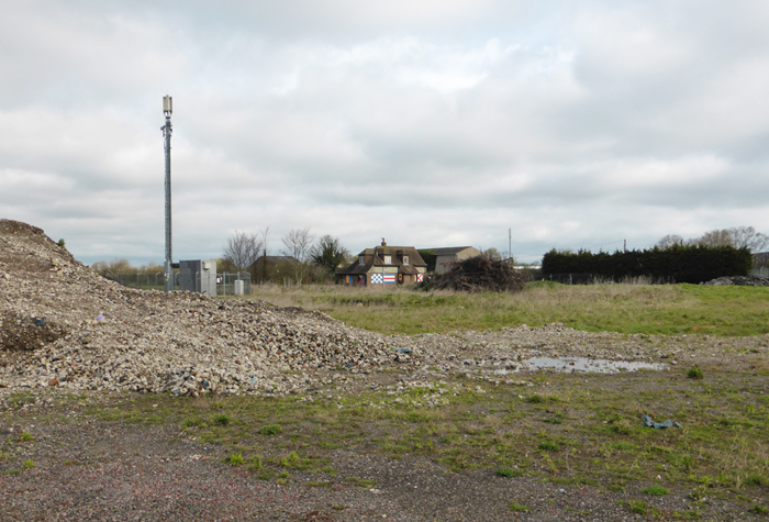 Empty seaside site with a lone house on the horizon